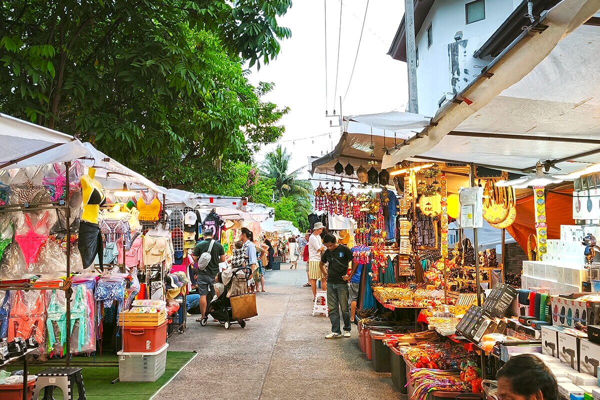 A quiet Samui daytime market with a handful of shoppers browsing stalls